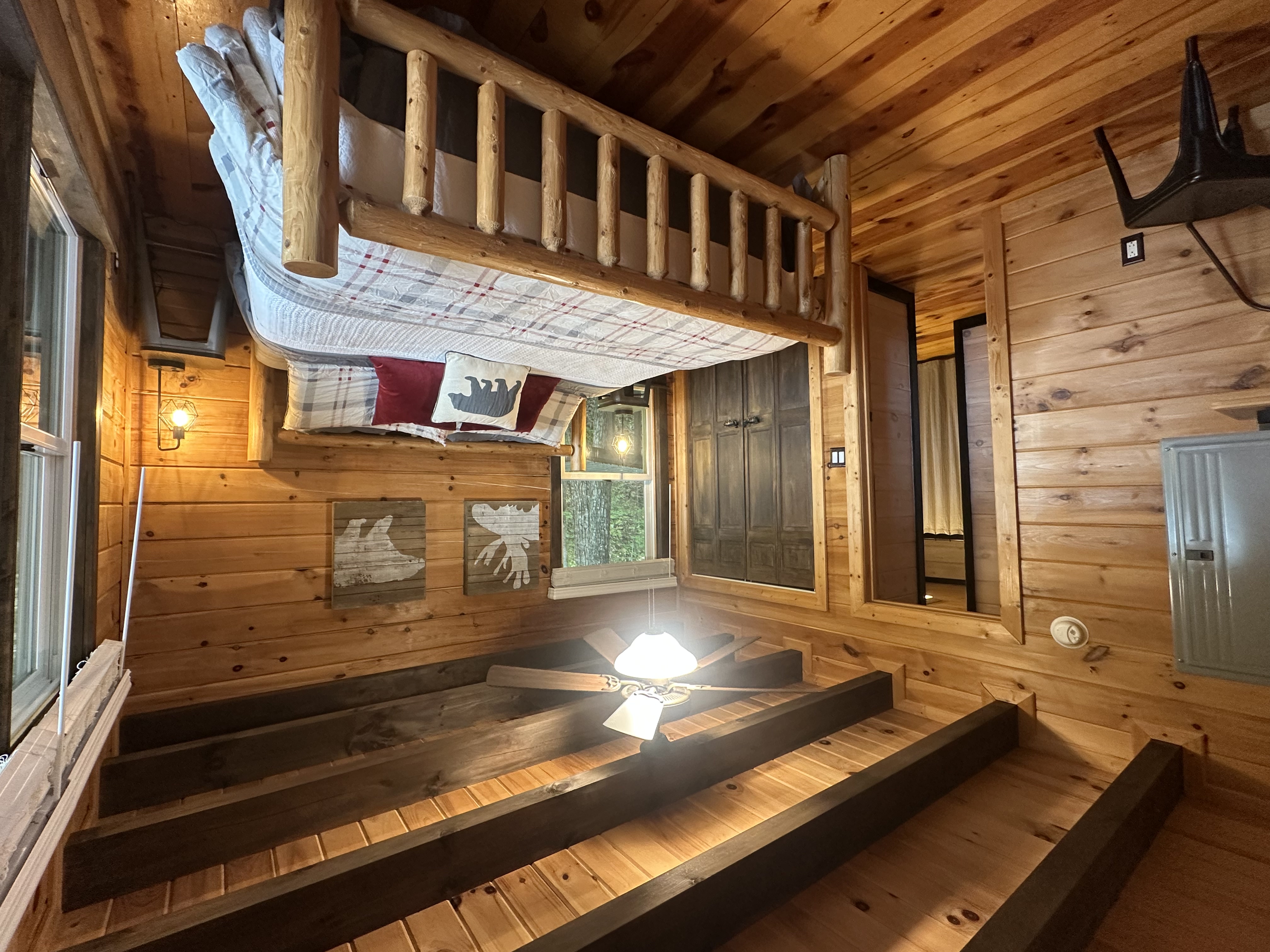 Main level king bedroom with rustic wood walls and warm cabin lighting.